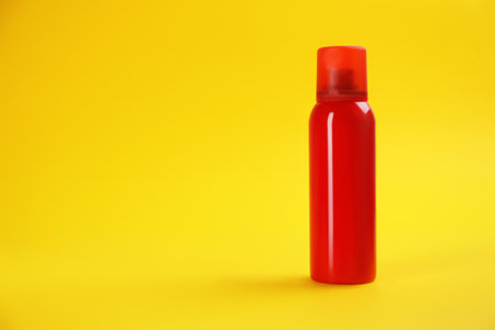 Bottle with insect repellent spray on yellow background, space for textの写真素材