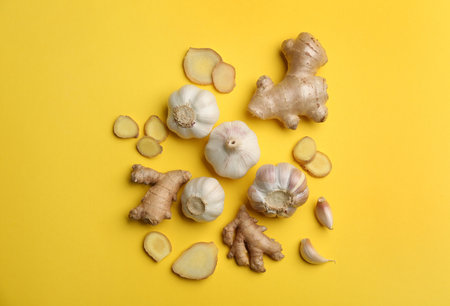 Ginger and garlic on yellow table, flat lay. natural cold remediesの写真素材