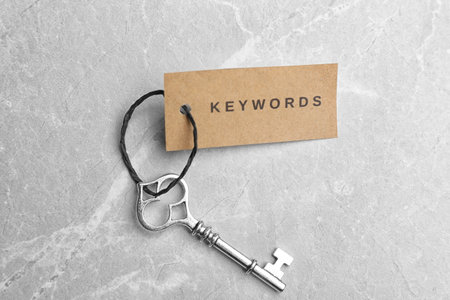 Vintage key and tag wIth word KEYWORDS on light gray table, top viewの写真素材