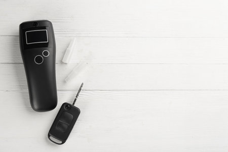 Modern breathalyser , mouthpieces and car key on white wooden background, flat lay. Space for textの写真素材