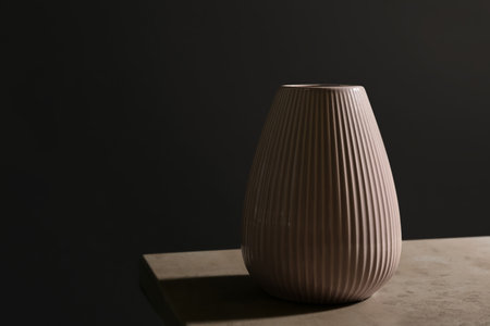 Stylish empty ceramic vase on table against black background, space for text