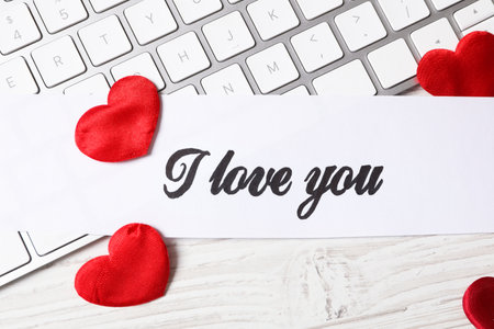 Card with text I Love You, red hearts and keyboard on white wooden background, flat layの写真素材