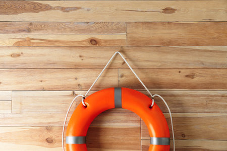 Orange lifebuoy and space for text on wooden background. Rescue equipmentの写真素材