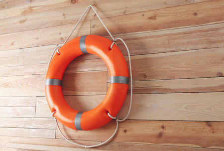 Orange lifebuoy and space for text on wooden background. Rescue equipmentの写真素材
