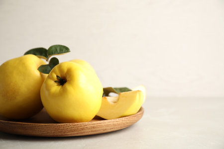 Fresh ripe organic quinces with leaves on light table. Space for textの写真素材