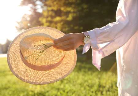 Young woman with straw hat and flowers outdoors on sunny day, closeupの写真素材