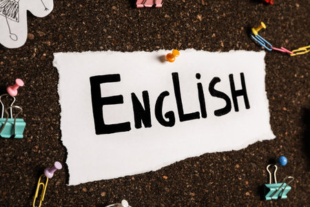 Sheet of paper with word English and different items on cork board, closeupの写真素材