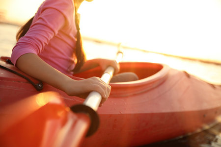Little girl kayaking on river at sunset, closeup. summer camp activitiesの写真素材