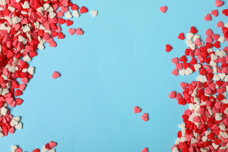 Bright heart shaped sprinkles on light blue background, flat lay. Space for textの写真素材