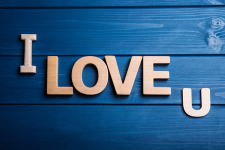 Phrase I Love U on blue wooden background, flat layの写真素材
