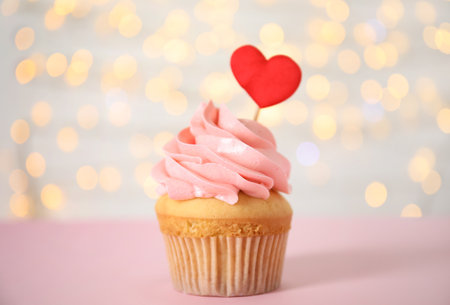 Tasty cupcake for Valentine's Day on pink table against blurred lightsの写真素材