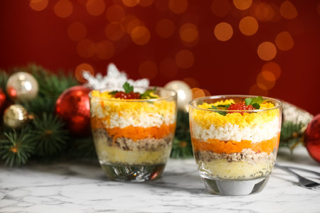 Traditional russian salad Mimosa and festive decor on table against blurred lightsの写真素材