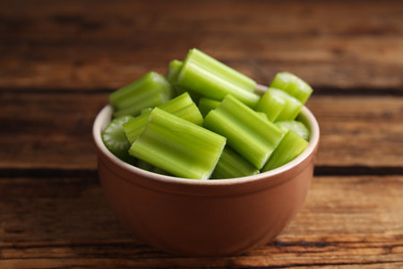 Cut celery in bowl on wooden tableの写真素材