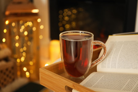 Cup of tea and book on wooden tray indoorsの写真素材