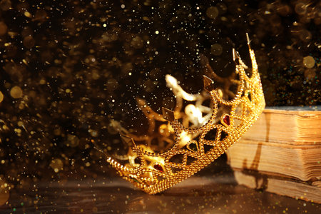 fantasy world. Beautiful golden crown and old books on table, bokeh effectの写真素材