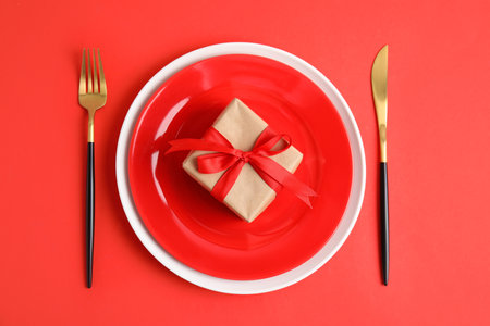 Elegant table setting for romantic dinner on red background, flat lay. Valentine's day celebrationの写真素材