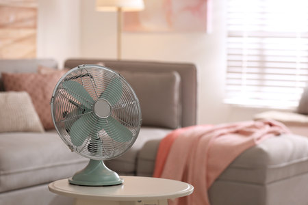 Modern electric fan on white table in living room. Space for textの写真素材