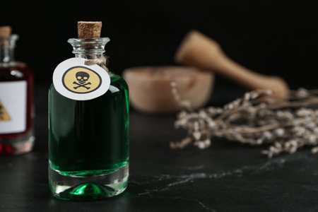 Glass bottle of poison with warning sign on black table. Space for textの写真素材