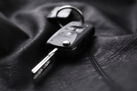 Modern car flip key with trinket on black leather, closeupの写真素材