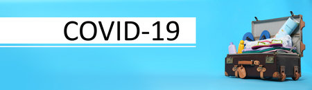 Coronavirus pandemic, lockdown measures. Packed travel suitcase and text COVID-19 on blue background, banner designの写真素材