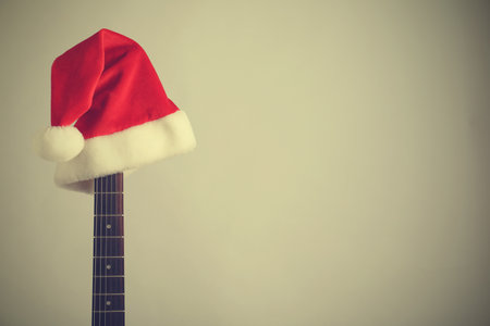 Guitar with Santa hat on light background, space for text. christmas musicの写真素材