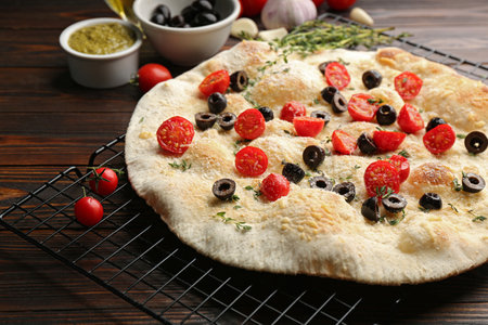 Focaccia bread with olives and tomatoes on wooden table, closeupの写真素材