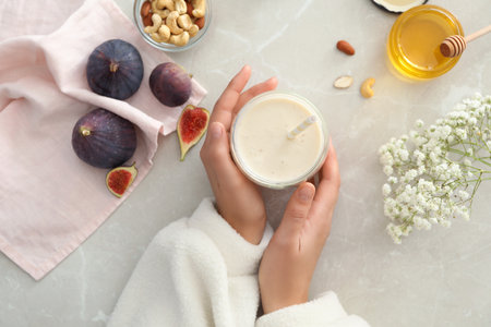 Woman with delicious fig smoothie at light table, top viewの写真素材