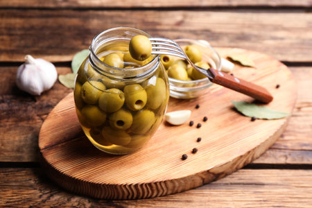 Glass jar of pickled olives on wooden tableの写真素材