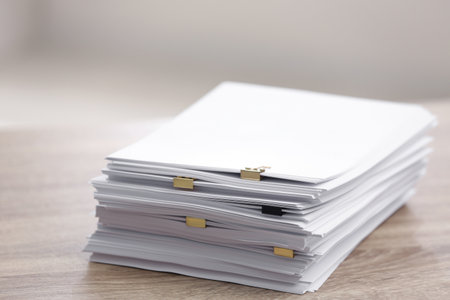 Stack of blank paper with binder clips on wooden table