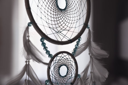 Beautiful dream catcher hanging against blurred background, closeup