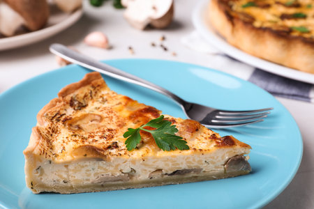 Delicious pie with mushrooms and cheese on light blue plate, closeupの写真素材