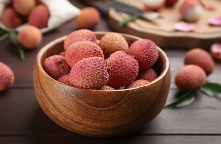Fresh ripe lychee fruits in bowl on wooden tableの写真素材