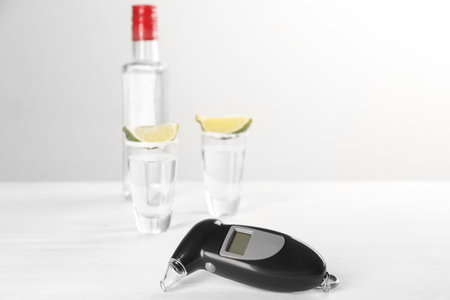 Modern breathalyser and alcohol on white table. Space for textの写真素材
