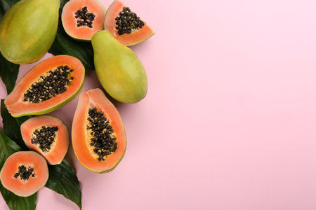 Fresh ripe papaya fruits with green leaves on pink background, flat lay. Space for textの写真素材