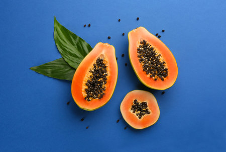 Fresh ripe papaya fruits with green leaves on blue background, flat layの写真素材