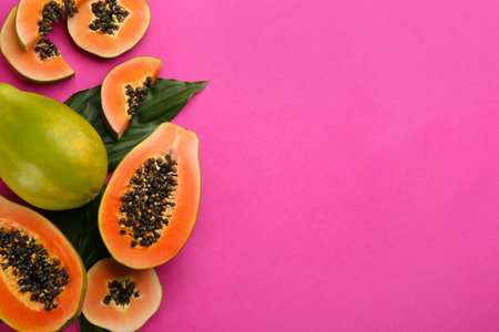 Fresh ripe papaya fruits with green leaves on purple background, flat lay. Space for textの写真素材