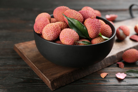 Fresh ripe lychee fruits in bowl on dark wooden tableの写真素材