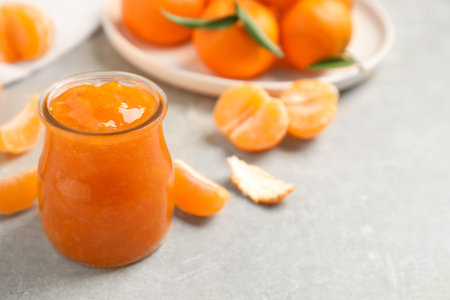 Tasty tangerine jam in glass jar on light gray table. Space for textの写真素材