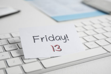 Paper note with phrase Friday 13 and keyboard on white table. Superstition of bad luckの写真素材
