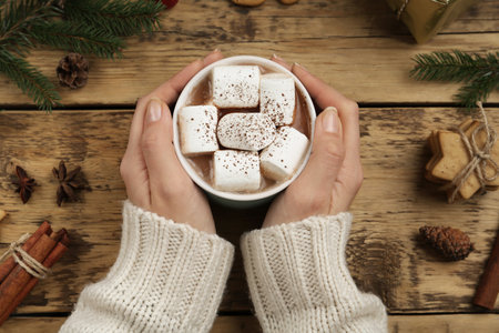 Woman with cup of delicious marshmallow cocoa at wooden table, top viewの写真素材