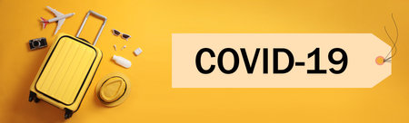 Coronavirus pandemic, lockdown measures. Flat lay composition with travel suitcase and text COVID-19 on orange background, banner designの写真素材