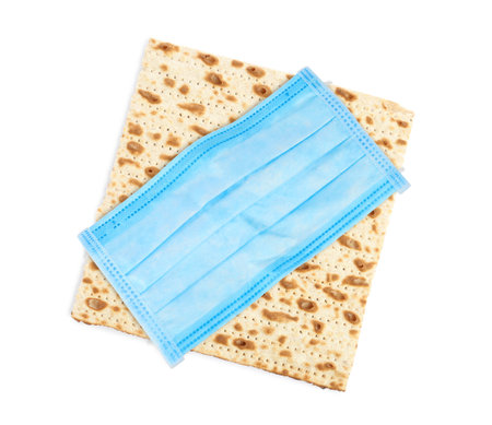 coronavirus pandemic. Passover matzo and protective face mask on white background, top view