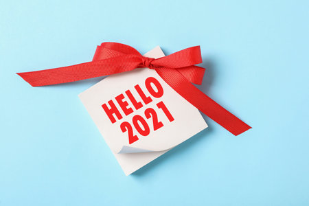 Memory stickers with text HELLO 2021 and red bow on light blue background, top viewの写真素材