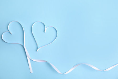 Hearts made of white ribbon on light blue background, flat lay with space for text. Valentine's day celebrationの写真素材