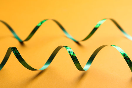 Shiny green serpentine streamers on orange background, closeupの写真素材