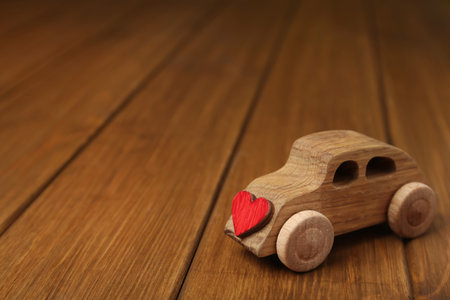 Wooden toy car with decorative heart on table, space for text. Happy Valentine's Dayの写真素材