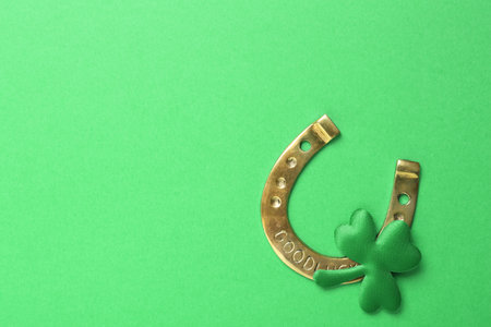Decorative clover leaf and horseshoe on green background, flat lay with space for text. St. Patrick's Day celebrationの写真素材