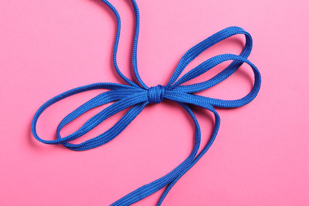 Blue shoelaces on pink background, top view