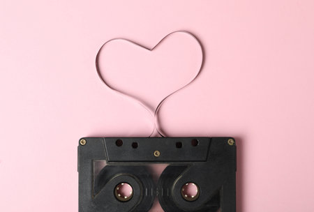 Music cassette and heart made with tape on pink background, top view. Listening love songの写真素材