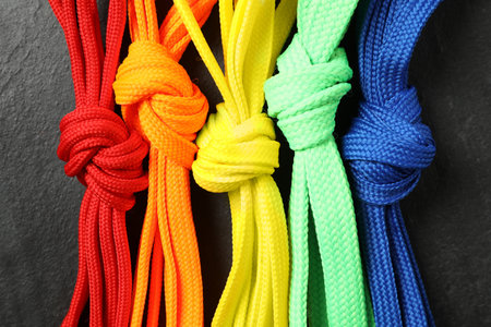 Colorful shoelaces on black background, flat lay